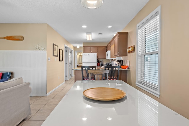 kitchen with white fridge, light tile flooring, and a textured ceiling