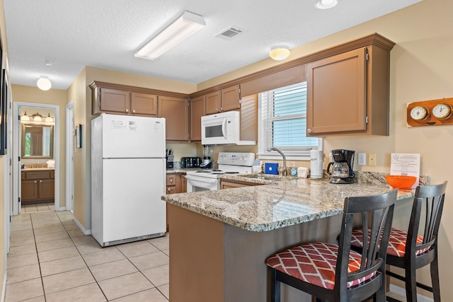 kitchen featuring a kitchen breakfast bar, kitchen peninsula, white appliances, and light tile floors