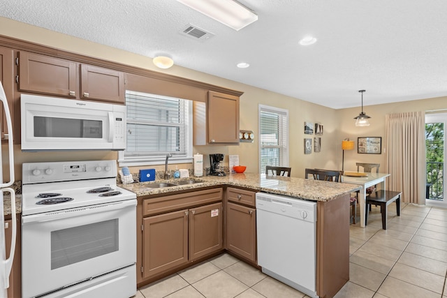 kitchen featuring white appliances, kitchen peninsula, decorative light fixtures, sink, and light tile floors