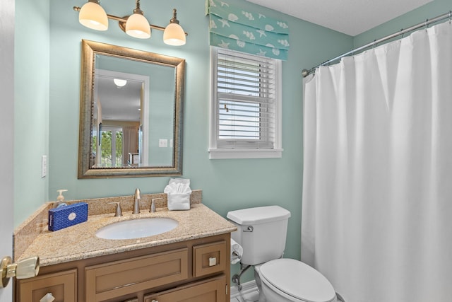 bathroom with a textured ceiling, large vanity, and toilet