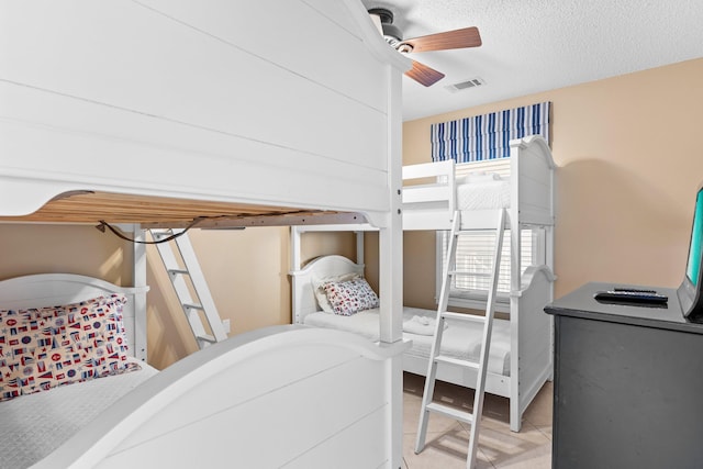 tiled bedroom featuring a textured ceiling and ceiling fan