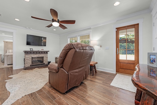 living room featuring ceiling fan, a fireplace, wood-type flooring, and ornamental molding