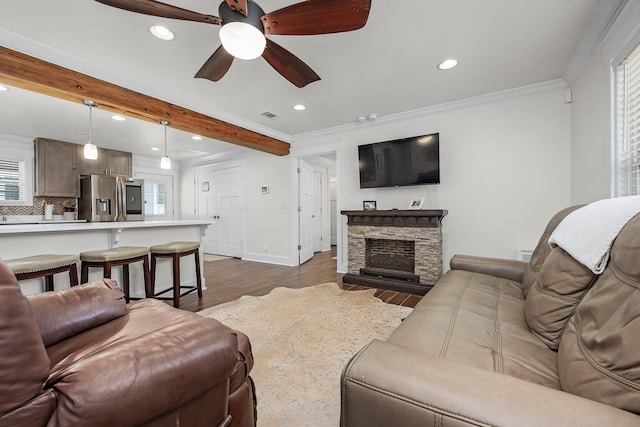 living room featuring ceiling fan, ornamental molding, a fireplace, a healthy amount of sunlight, and dark hardwood / wood-style flooring