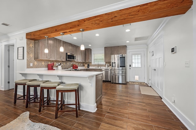 kitchen featuring a kitchen breakfast bar, decorative light fixtures, dark hardwood / wood-style flooring, kitchen peninsula, and stainless steel appliances