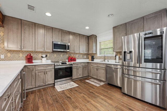 521 W Juniper Ave, Defuniak Springs, FL 32433 - kitchen featuring appliances with stainless steel finishes, a sink, decorative backsplash, dark wood-style flooring, and recessed lighting