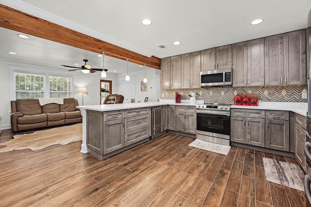 kitchen with kitchen peninsula, pendant lighting, dark hardwood / wood-style floors, and appliances with stainless steel finishes