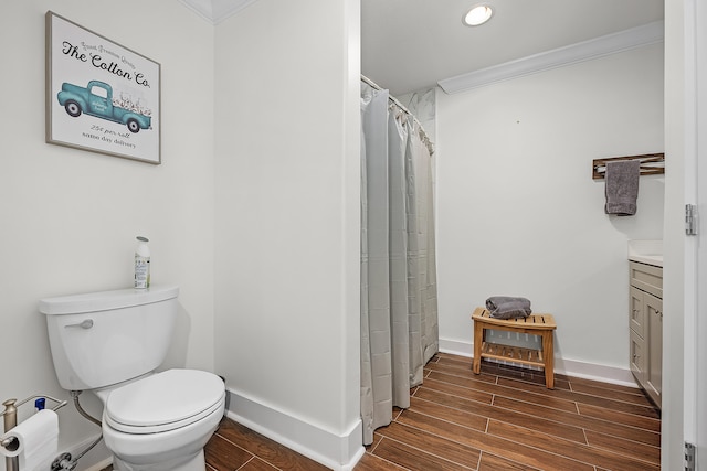 bathroom featuring toilet, hardwood / wood-style floors, vanity, and ornamental molding