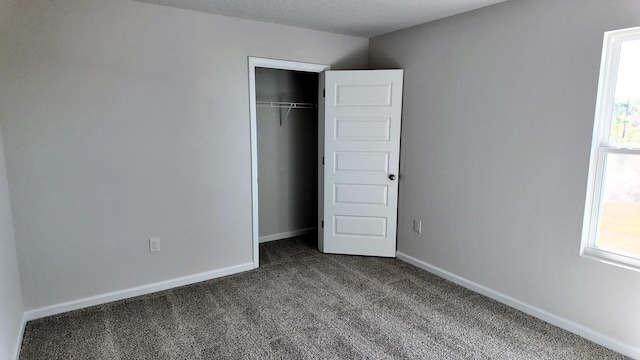 unfurnished bedroom featuring carpet flooring, a textured ceiling, and a closet