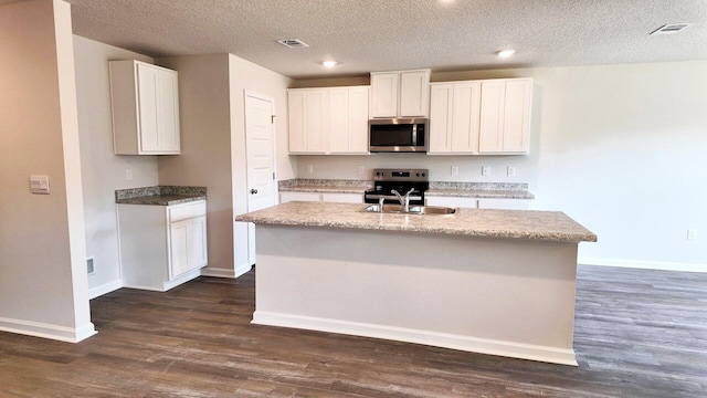 kitchen with dark hardwood / wood-style flooring, white cabinetry, a center island with sink, and appliances with stainless steel finishes