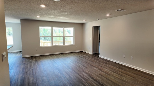 spare room featuring a textured ceiling and dark hardwood / wood-style floors