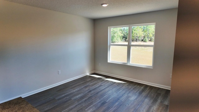 spare room with a textured ceiling and dark hardwood / wood-style flooring