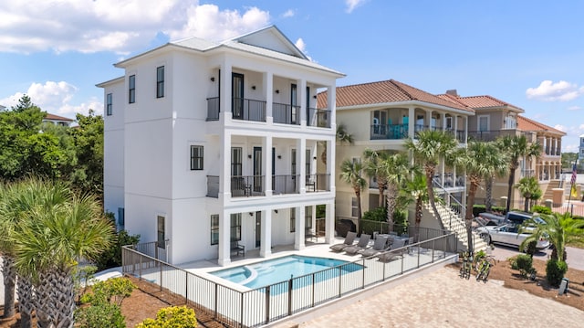 back of property with an in ground hot tub and a balcony