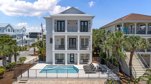 rear view of house with a patio area, a balcony, and a swimming pool with hot tub