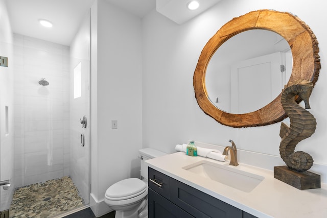 bathroom featuring a tile shower, vanity, and toilet