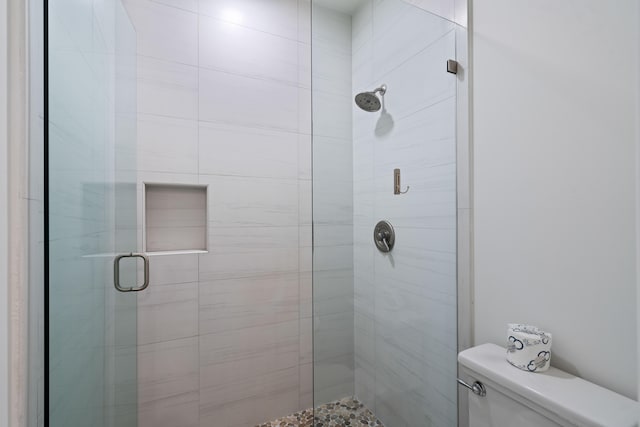 bathroom with a shower with shower door and toilet