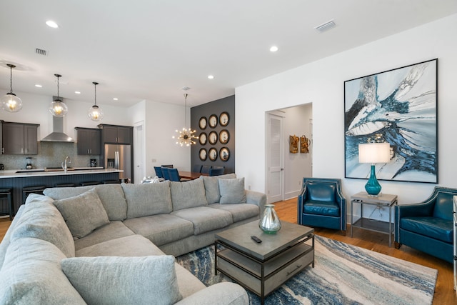 living room featuring a notable chandelier, sink, and hardwood / wood-style flooring