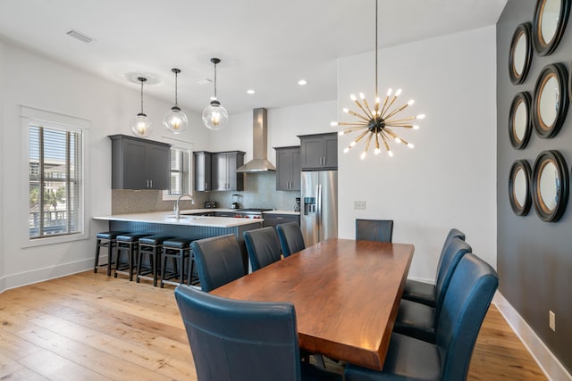 dining room with a chandelier, sink, and light wood-type flooring