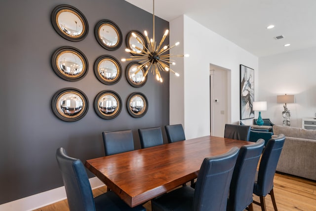 dining space with light wood-type flooring and an inviting chandelier