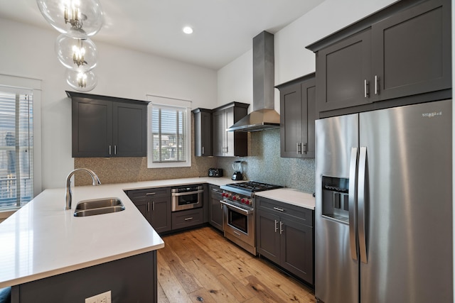 kitchen with stainless steel appliances, wall chimney range hood, tasteful backsplash, and light wood-type flooring