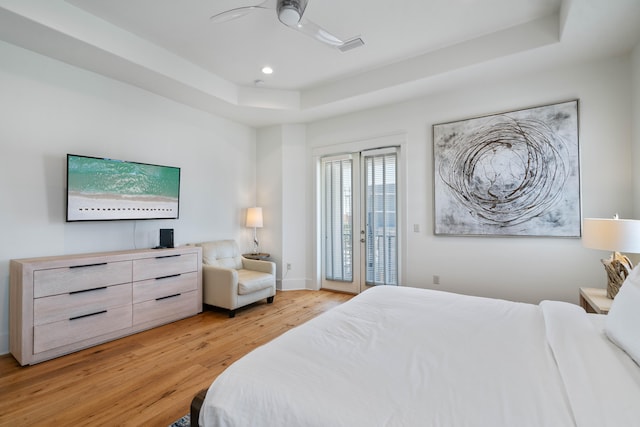 bedroom with a raised ceiling, ceiling fan, light hardwood / wood-style floors, and access to outside