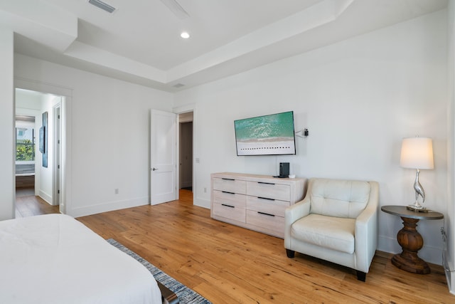 bedroom featuring light wood-type flooring and a raised ceiling