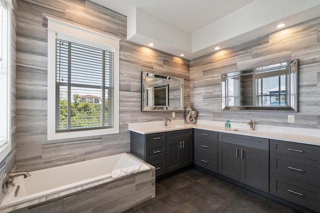 bathroom with tile walls, tile flooring, a relaxing tiled bath, and double sink vanity