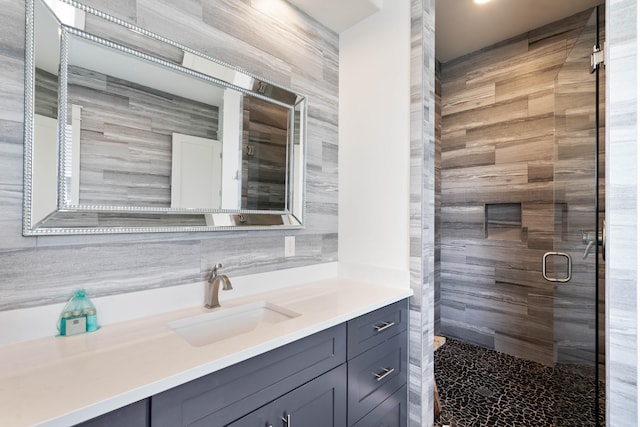 bathroom with vanity, tile walls, and a shower with door