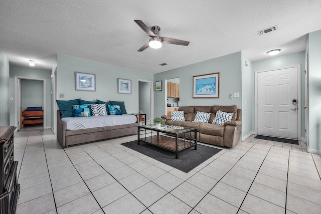 living room with ceiling fan, a textured ceiling, and light tile floors