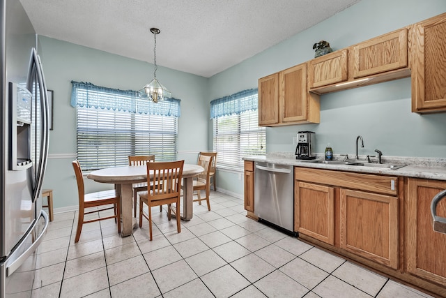 kitchen with appliances with stainless steel finishes, decorative light fixtures, light tile floors, sink, and a chandelier