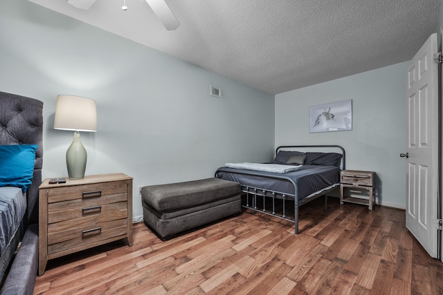 bedroom with ceiling fan, hardwood / wood-style flooring, and a textured ceiling