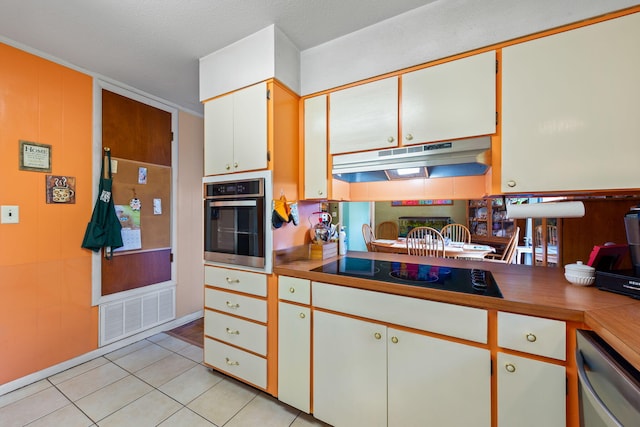 kitchen with appliances with stainless steel finishes, white cabinetry, and light tile flooring