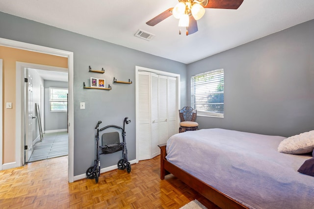 bedroom featuring ceiling fan, a closet, and light parquet flooring