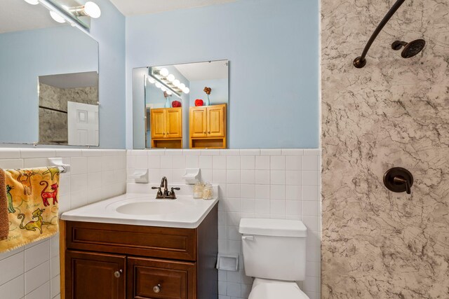 bathroom featuring tile walls, backsplash, toilet, a tile shower, and vanity