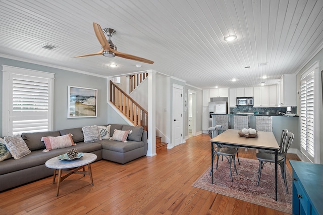 living room featuring ceiling fan, light wood-type flooring, ornamental molding, and wooden ceiling