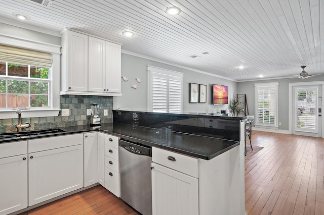 kitchen featuring white cabinetry, sink, light hardwood / wood-style flooring, stainless steel dishwasher, and ornamental molding