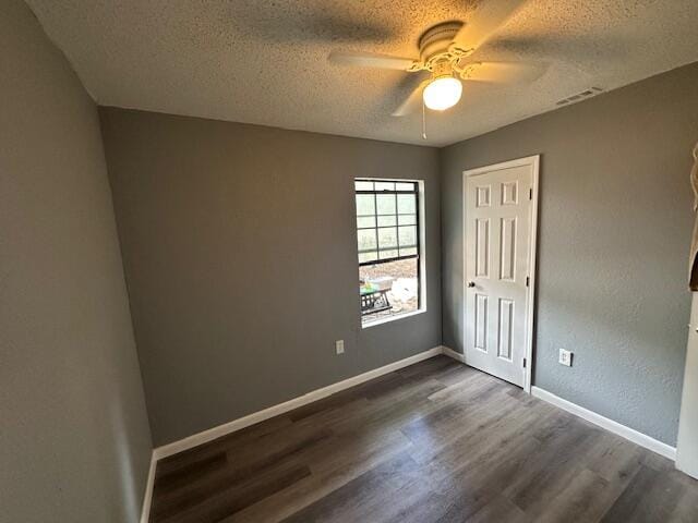 spare room with a textured ceiling, dark wood-type flooring, and ceiling fan