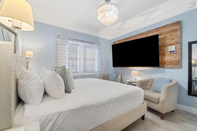 bedroom featuring crown molding, wood-type flooring, and an inviting chandelier