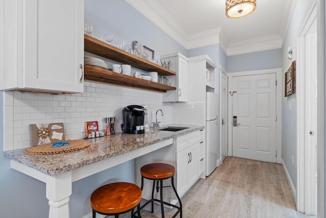 kitchen with sink, light hardwood / wood-style floors, white cabinets, and backsplash