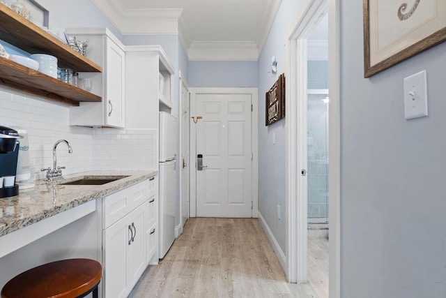 kitchen with light hardwood / wood-style floors, crown molding, tasteful backsplash, sink, and white cabinets