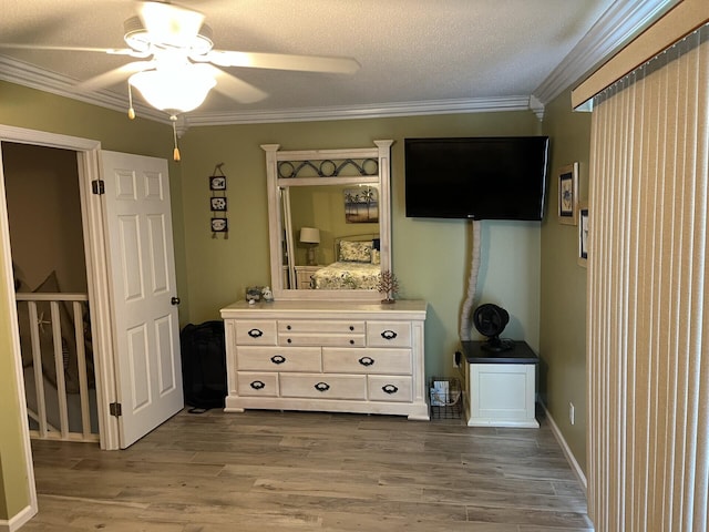 unfurnished bedroom featuring wood-type flooring, a textured ceiling, ceiling fan, and crown molding