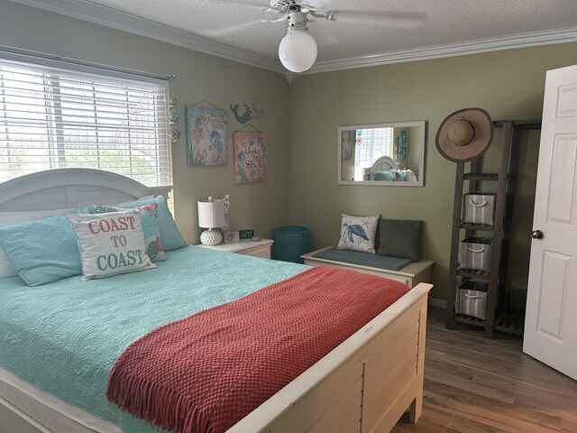 bedroom featuring wood-type flooring, a textured ceiling, ceiling fan, and crown molding