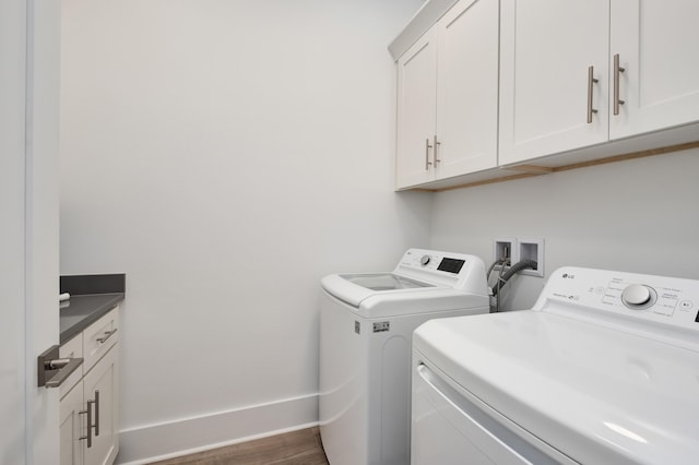 laundry room featuring cabinets, dark wood-type flooring, and washing machine and clothes dryer