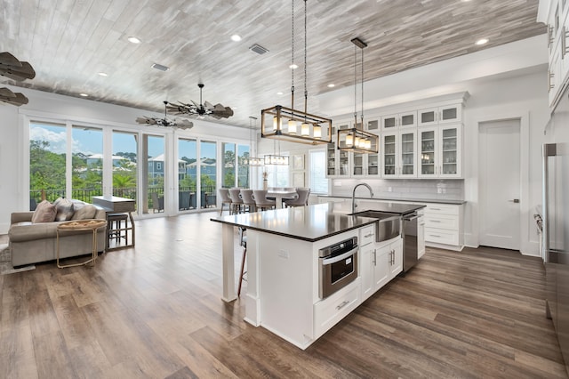 kitchen with a kitchen bar, stainless steel appliances, a kitchen island with sink, sink, and white cabinets