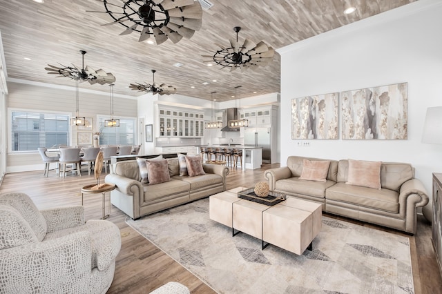 living room with ceiling fan with notable chandelier, light hardwood / wood-style flooring, and wooden ceiling