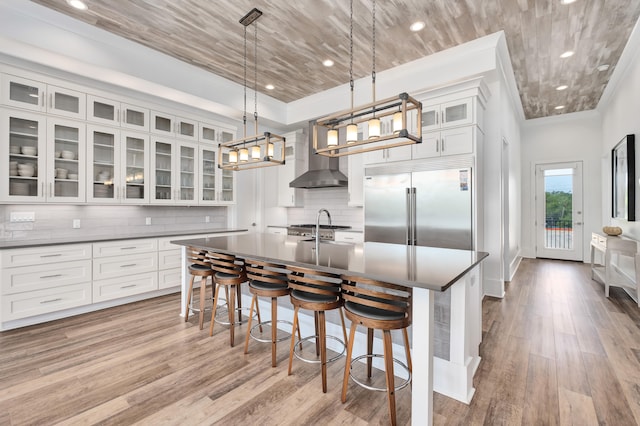 kitchen featuring decorative backsplash, white cabinets, decorative light fixtures, and stainless steel built in refrigerator