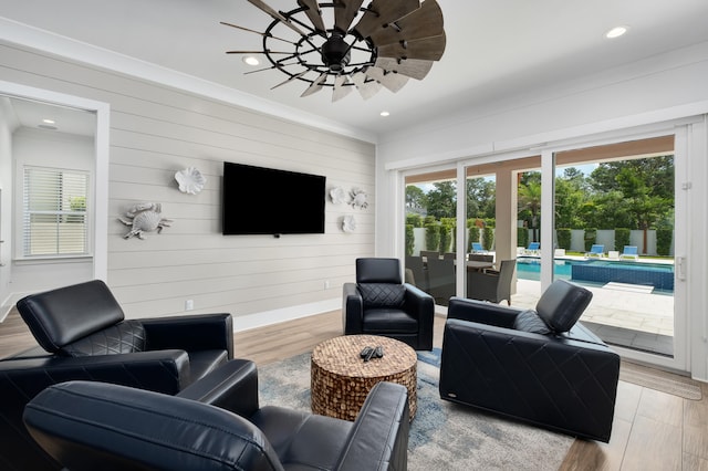 living room with hardwood / wood-style flooring, ceiling fan, and wooden walls