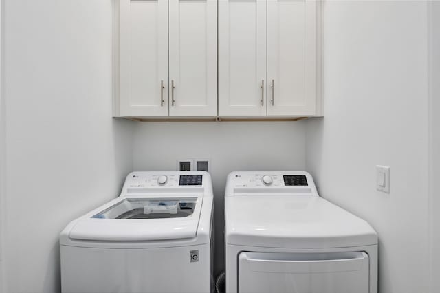 clothes washing area featuring cabinets and washing machine and clothes dryer