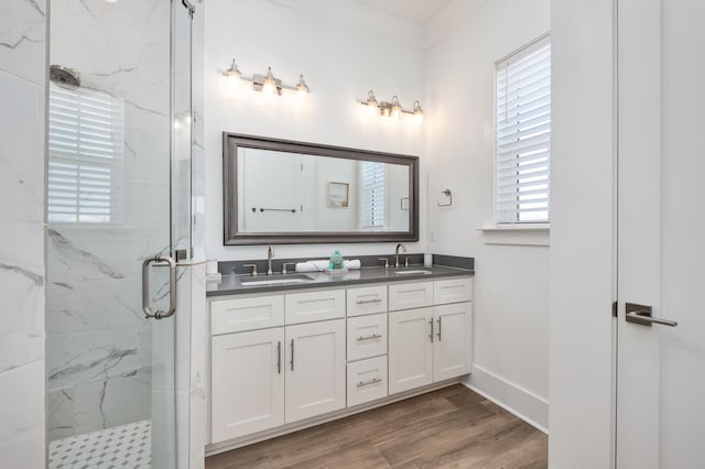 bathroom featuring hardwood / wood-style floors, vanity, a shower with door, and crown molding