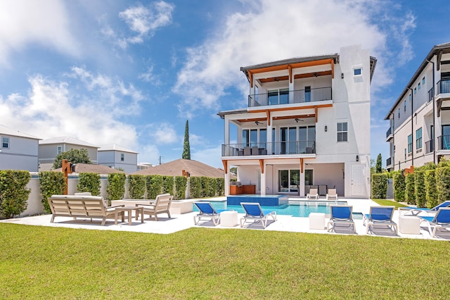 back of house featuring a lawn, ceiling fan, an outdoor living space, a balcony, and a patio area