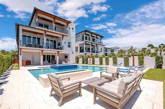 back of property featuring ceiling fan, a patio area, a balcony, and a fenced in pool